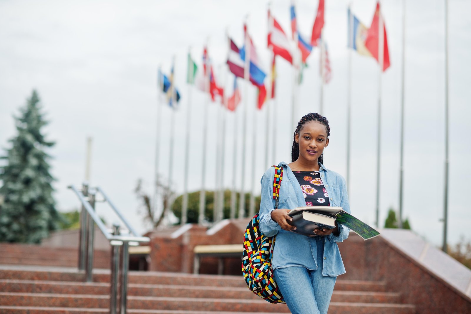 african-student-female-posed-with-backpack-school-items-yard-university-against-flags-different-countries