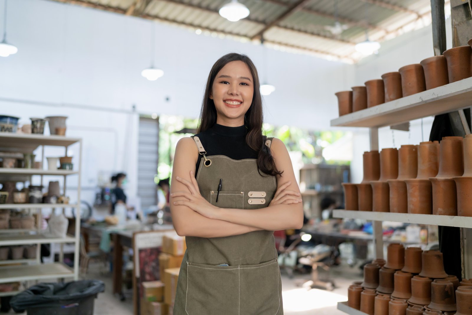 asia-female-ceramist-with-apron-hand-confident-chest-her-workshop-clay-sculpture-studio-with-positive-smiling-warm-welcome-ready-start-new-factory-ceramic-workshop-with-new-collection-work