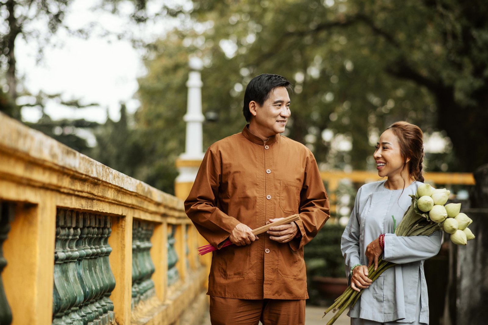 front-view-woman-man-holding-bouquet-flowers-temple-incense