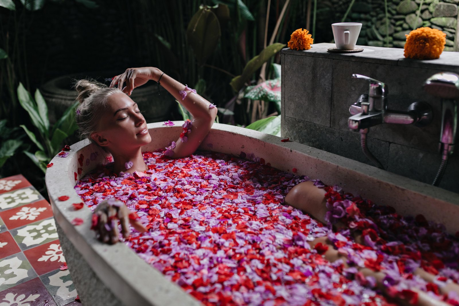 pleasant-woman-with-tanned-skin-lying-bath-with-eyes-closed-indoor-shot-cute-blonde-lady-enjoying-spa-with-rose-petals
